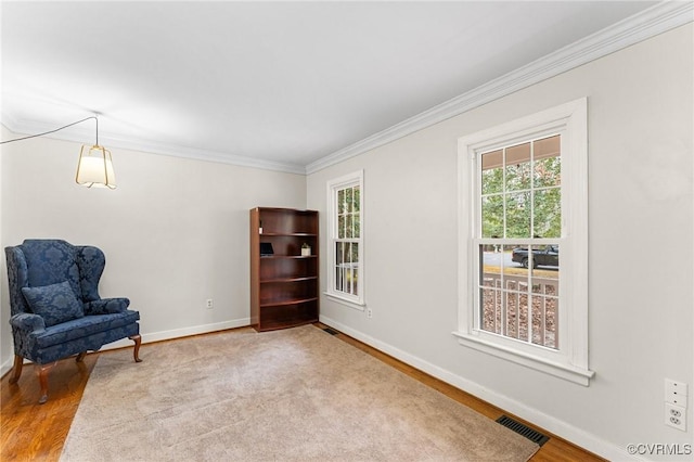 sitting room with visible vents, wood finished floors, baseboards, and ornamental molding