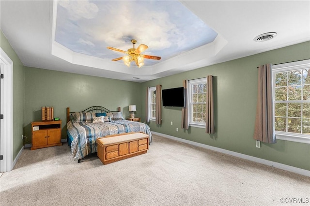 bedroom featuring a tray ceiling, baseboards, visible vents, and carpet flooring