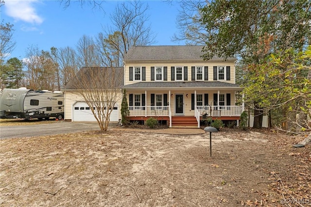 colonial home with a porch, driveway, and a garage