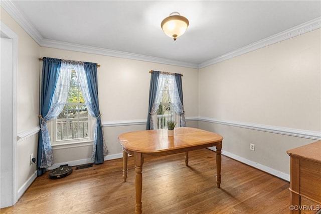 dining area with baseboards, a healthy amount of sunlight, wood finished floors, and crown molding