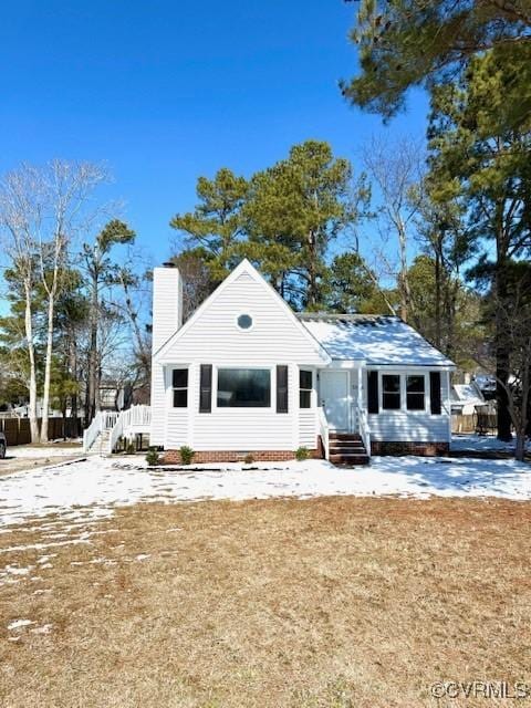 back of house with entry steps, a chimney, and a yard