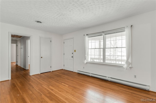 interior space with visible vents, a baseboard heating unit, baseboards, light wood-style floors, and a textured ceiling