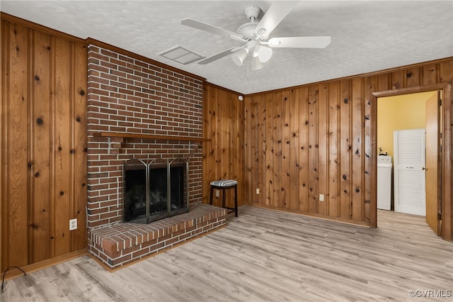 unfurnished living room with wood walls, a fireplace, washer / clothes dryer, and wood finished floors