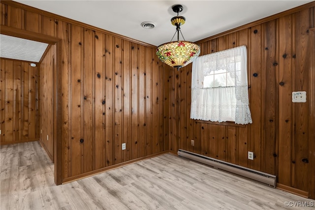 unfurnished dining area featuring a baseboard heating unit, wooden walls, visible vents, and light wood finished floors