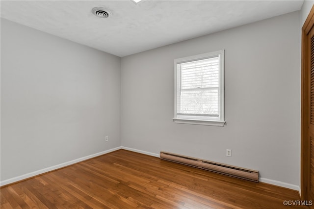 spare room with visible vents, wood finished floors, baseboards, and a baseboard radiator