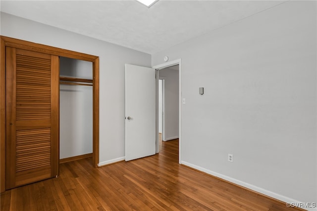 unfurnished bedroom with hardwood / wood-style flooring, baseboards, and a closet