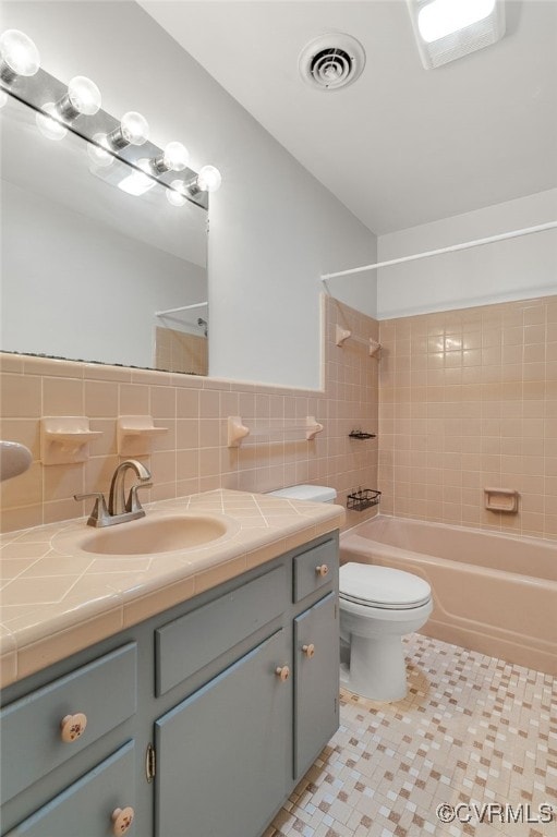 full bathroom with visible vents, tile walls, toilet, shower / bathtub combination, and vanity