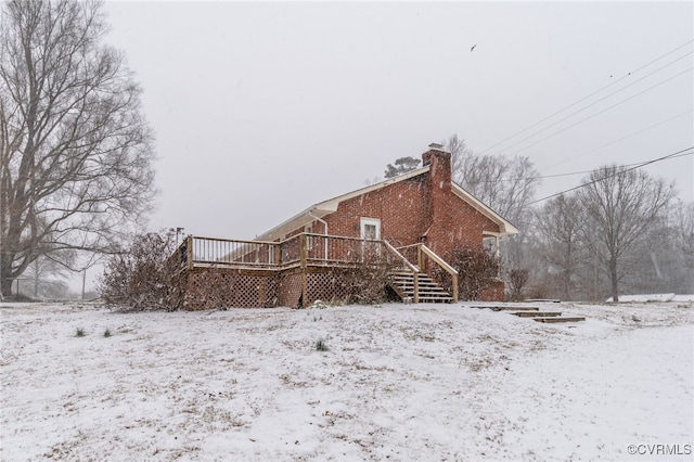 exterior space featuring brick siding, a wooden deck, and a chimney