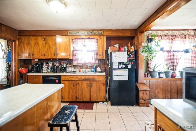 kitchen with black appliances, light countertops, a sink, and brown cabinetry