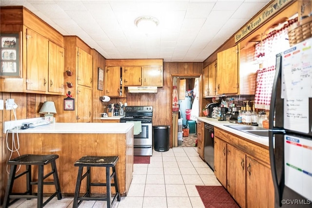 kitchen with under cabinet range hood, a kitchen breakfast bar, light countertops, brown cabinets, and black appliances