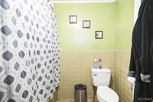 full bathroom with a shower with curtain, wainscoting, tile walls, and toilet