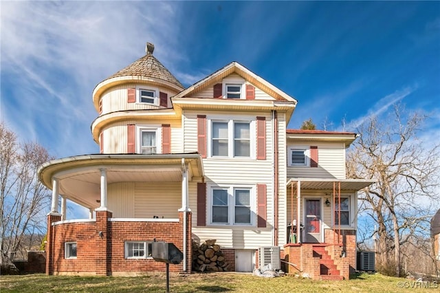 victorian home with central AC unit, a porch, and a front yard