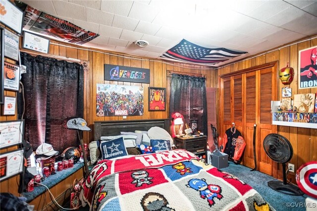 bedroom with a closet, carpet flooring, wood walls, and visible vents