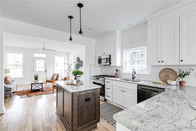 kitchen featuring stainless steel appliances, decorative light fixtures, a sink, and white cabinetry