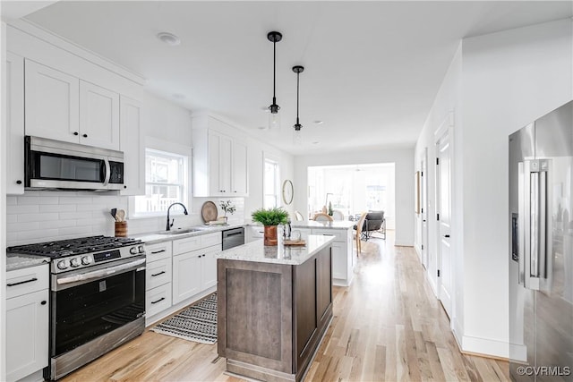 kitchen featuring stainless steel appliances, a center island, white cabinets, decorative backsplash, and pendant lighting