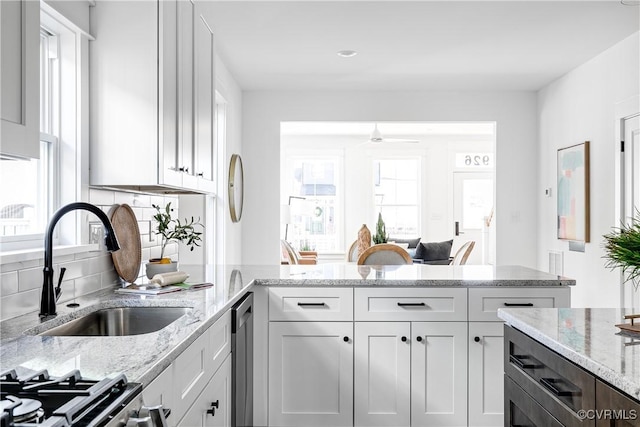 kitchen featuring a sink, white cabinetry, and light stone counters