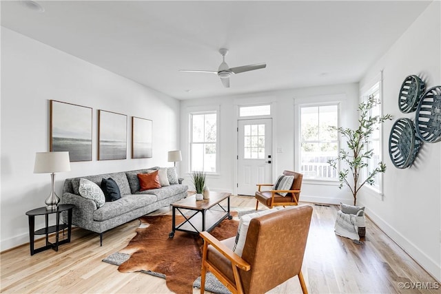 living room featuring light wood finished floors, a ceiling fan, and baseboards