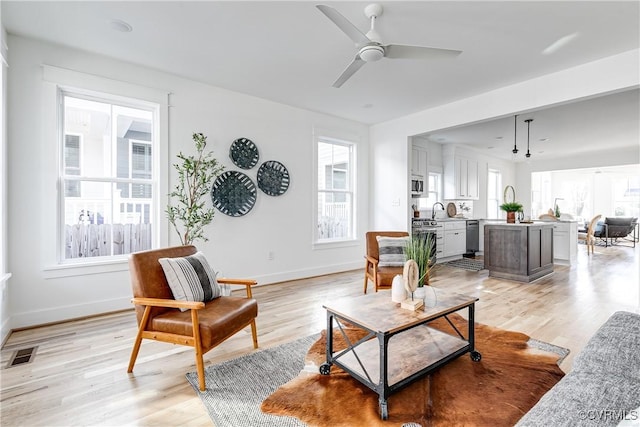 living area with light wood finished floors, visible vents, and a ceiling fan