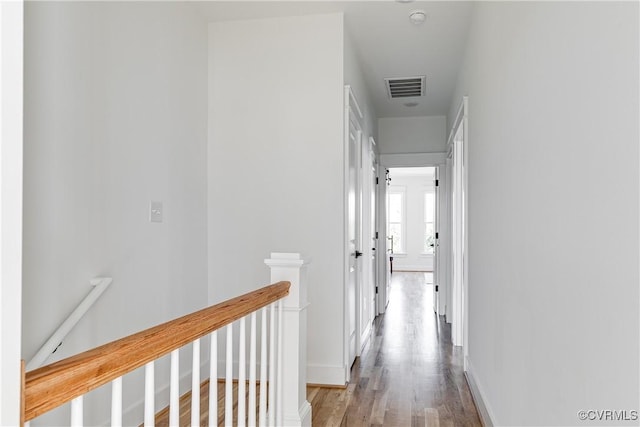 corridor with visible vents, light wood-style flooring, an upstairs landing, and baseboards