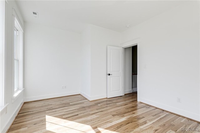 empty room with visible vents, light wood-style flooring, and baseboards