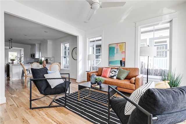 living area with ceiling fan, light wood-type flooring, and baseboards