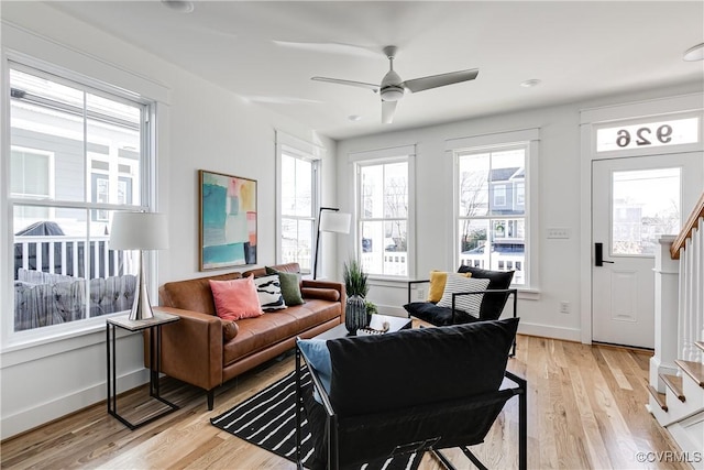 living area with stairway, light wood-style flooring, and baseboards