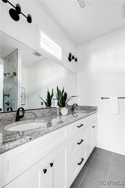 bathroom with double vanity, a stall shower, tile patterned flooring, and a sink