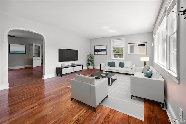 living room with baseboards, arched walkways, and wood finished floors