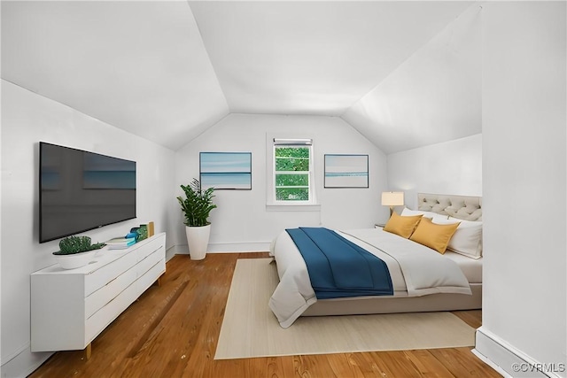 bedroom with lofted ceiling, wood finished floors, and baseboards