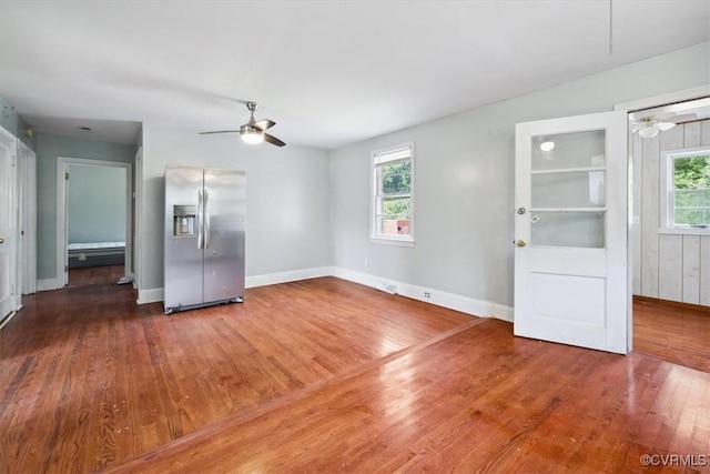 unfurnished living room featuring baseboards, a healthy amount of sunlight, wood finished floors, and a ceiling fan