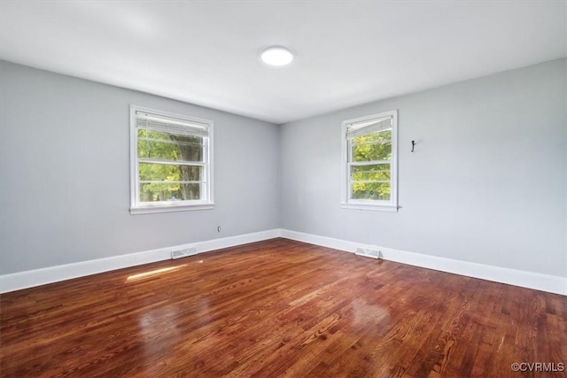 spare room featuring dark wood finished floors, baseboards, and visible vents