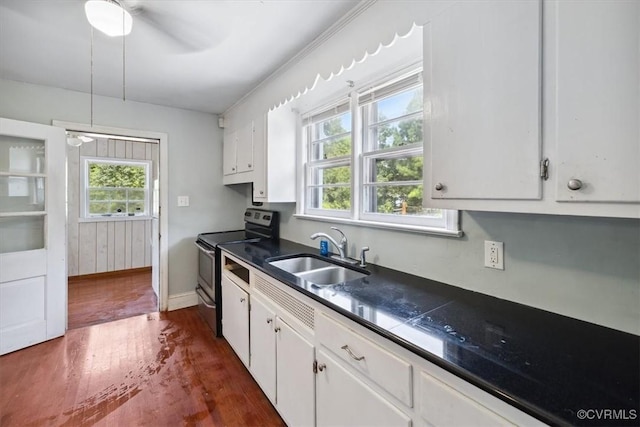 kitchen with dark wood finished floors, electric range, a sink, white cabinetry, and dark countertops