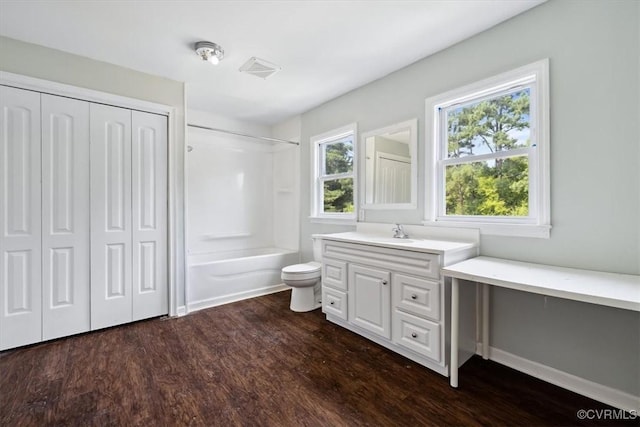 bathroom with visible vents, toilet, wood finished floors, vanity, and  shower combination