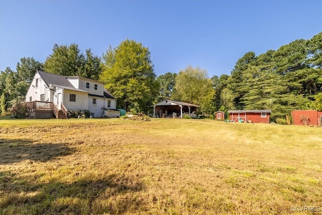 view of yard featuring a shed, a wooden deck, and an outdoor structure