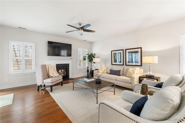 living area featuring wood finished floors, a ceiling fan, visible vents, and a healthy amount of sunlight