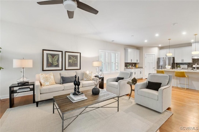 living room featuring recessed lighting, ceiling fan, baseboards, and light wood-style floors