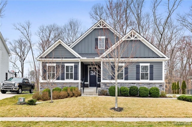 craftsman inspired home with board and batten siding, a front yard, and stone siding