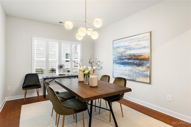 dining room with visible vents, an inviting chandelier, baseboards, and wood finished floors