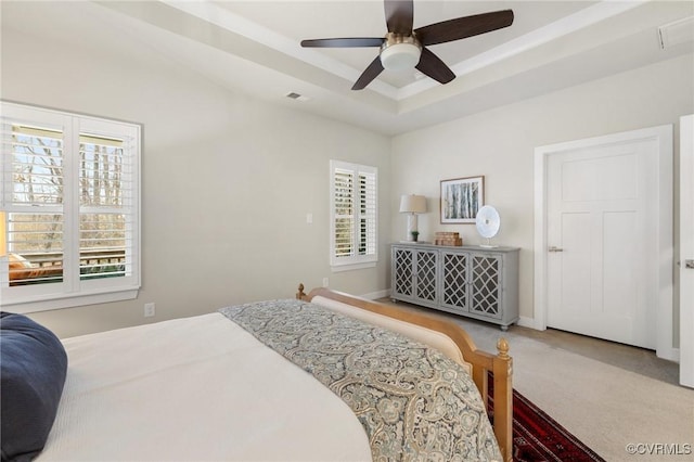 carpeted bedroom featuring visible vents, a raised ceiling, baseboards, and a ceiling fan