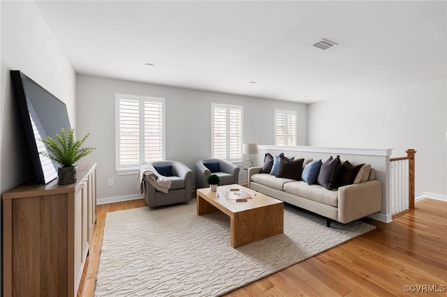 living area featuring light wood-style flooring, baseboards, and visible vents