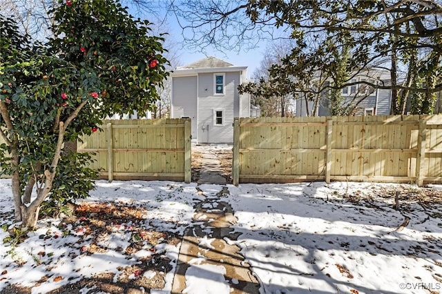 yard layered in snow featuring fence and a gate