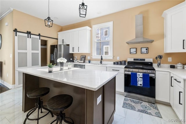 kitchen featuring hanging light fixtures, wall chimney range hood, appliances with stainless steel finishes, and white cabinets