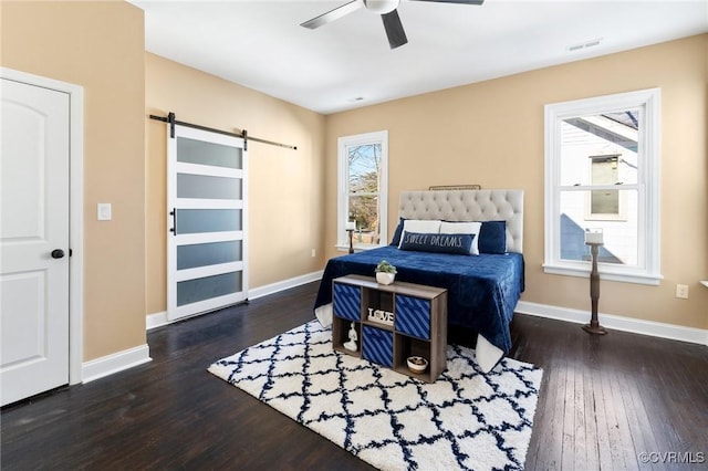 bedroom featuring visible vents, dark wood finished floors, baseboards, and a barn door