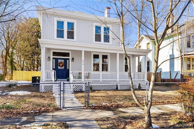 view of front of house with a fenced front yard, a gate, a chimney, and a porch