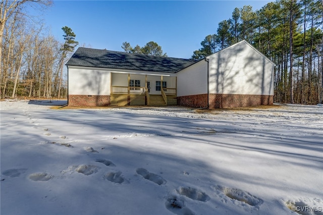 snow covered property with covered porch and crawl space