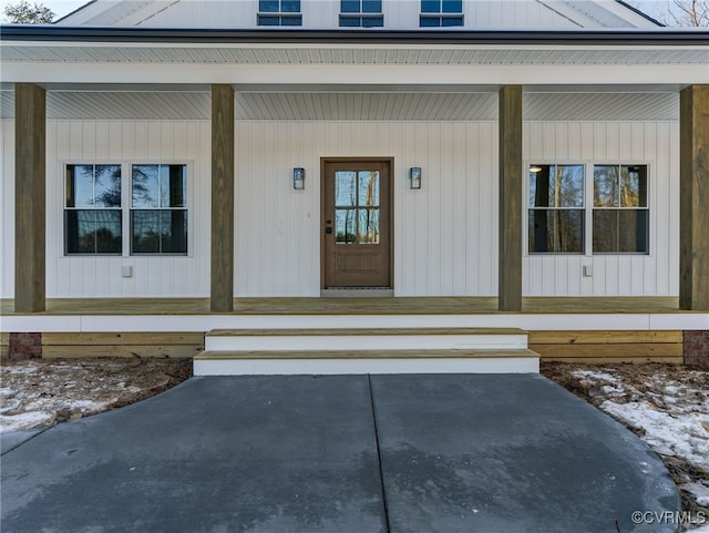 snow covered property entrance featuring a porch