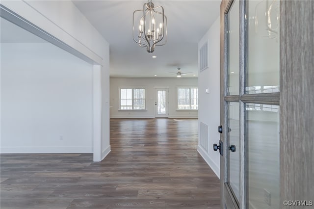 foyer entrance with baseboards, visible vents, dark wood finished floors, and ceiling fan with notable chandelier