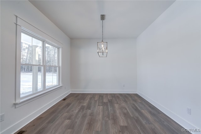 unfurnished dining area with a chandelier, dark wood-type flooring, and baseboards