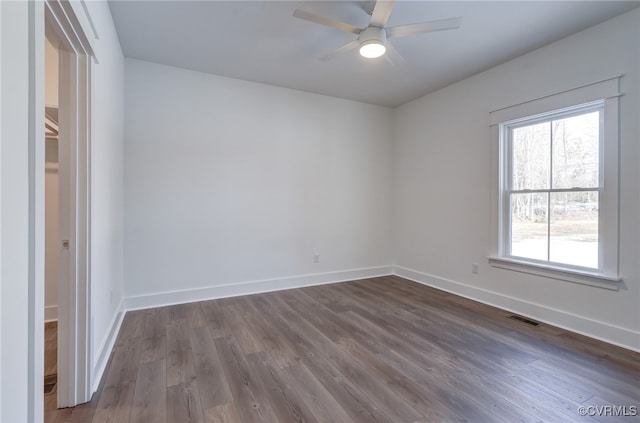 spare room with a ceiling fan, visible vents, baseboards, and wood finished floors