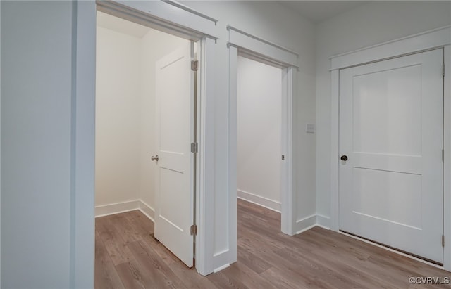 hallway featuring light wood-style flooring and baseboards